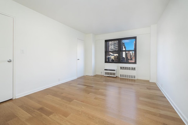 240 E 76th St Unit 7-M, New York City, NY 10021 - unfurnished room with radiator heating unit and light wood-style flooring