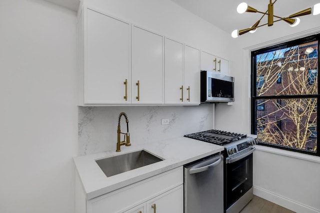 kitchen featuring sink, white cabinetry, stainless steel appliances, tasteful backsplash, and light stone countertops