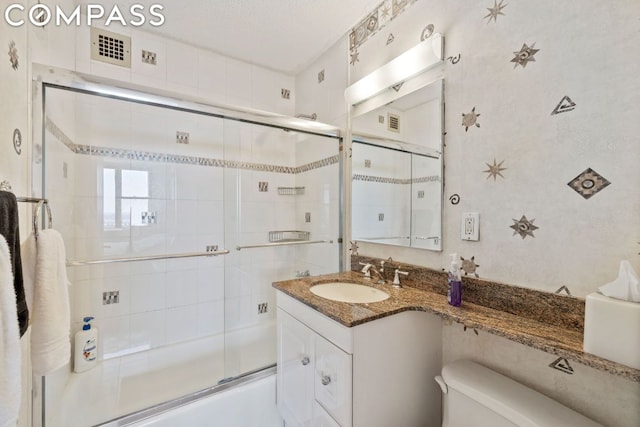 full bathroom featuring toilet, bath / shower combo with glass door, vanity, and a textured ceiling