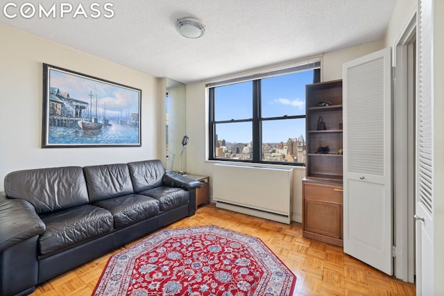 living room featuring light parquet flooring, baseboard heating, and a textured ceiling