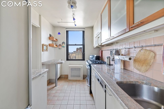 kitchen featuring white appliances, white cabinets, track lighting, backsplash, and light tile patterned flooring