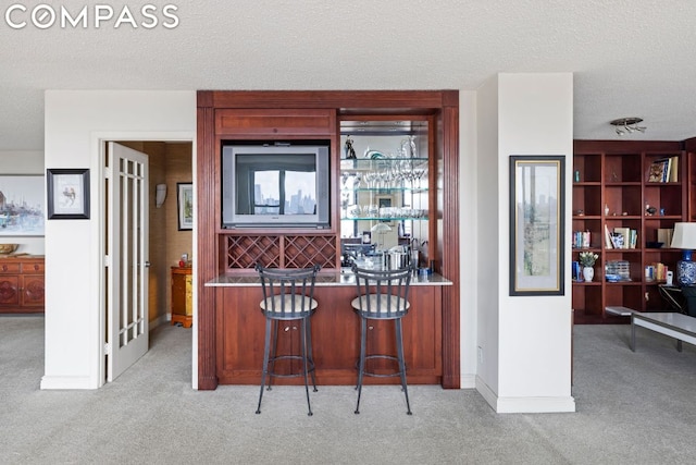 kitchen with light colored carpet, a kitchen breakfast bar, and a textured ceiling