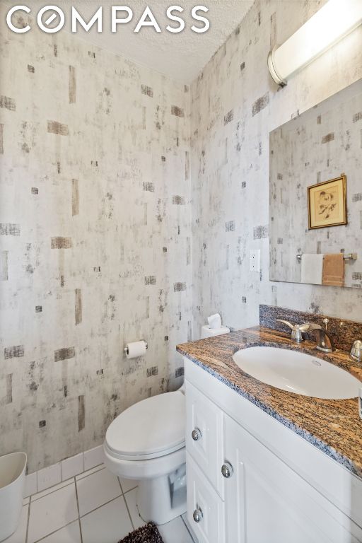 bathroom featuring toilet, tile patterned flooring, a textured ceiling, and vanity