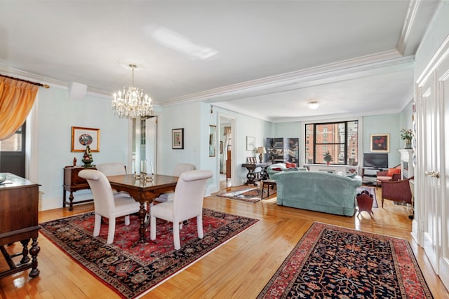 dining room with ornamental molding, wood-type flooring, and an inviting chandelier