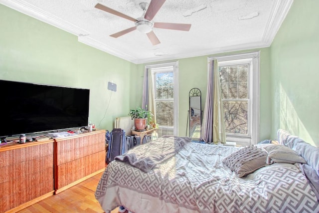 bedroom featuring hardwood / wood-style floors, a textured ceiling, radiator, ornamental molding, and ceiling fan