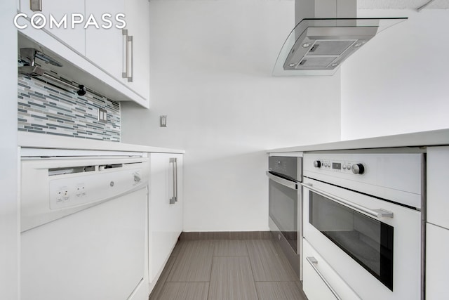 kitchen with white appliances, baseboards, decorative backsplash, light countertops, and white cabinets