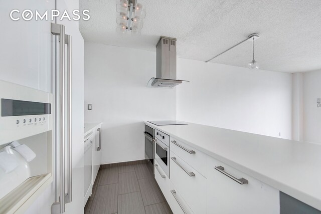 kitchen featuring white appliances, ventilation hood, light countertops, white cabinets, and a textured ceiling