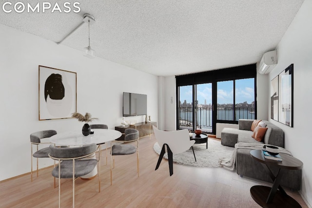 living room featuring light wood-type flooring, a textured ceiling, and an AC wall unit