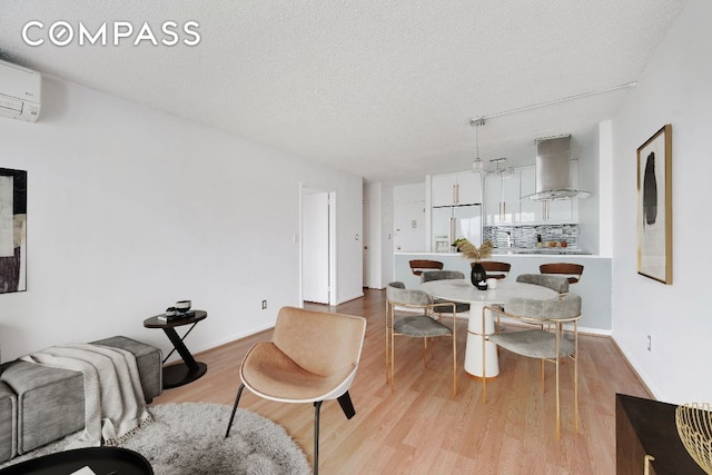 living room with an AC wall unit, a textured ceiling, and light wood-type flooring