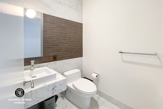 bathroom featuring marble finish floor, a sink, toilet, and baseboards