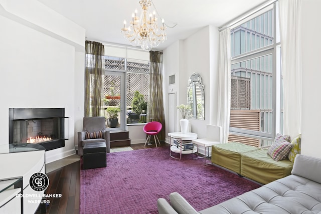 interior space with a fireplace with flush hearth, baseboards, wood finished floors, and an inviting chandelier