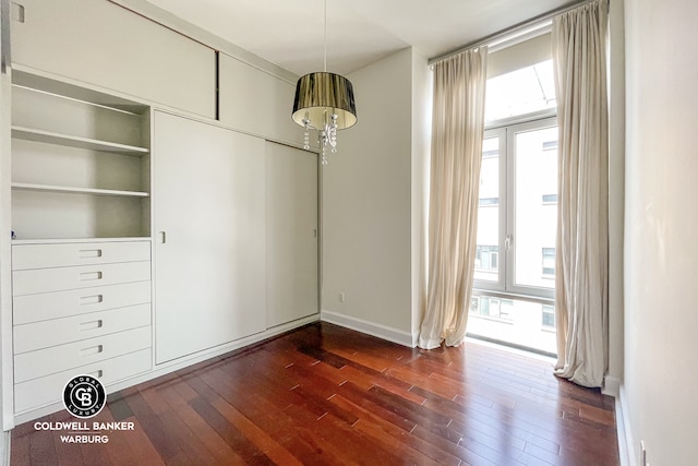 unfurnished dining area with dark wood-type flooring, plenty of natural light, and baseboards