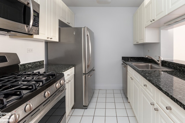 kitchen featuring appliances with stainless steel finishes, sink, white cabinets, dark stone counters, and light tile patterned floors