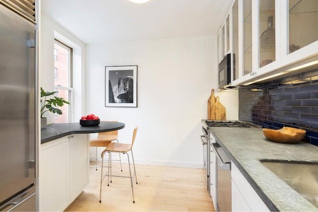 kitchen with sink, tasteful backsplash, stainless steel appliances, light hardwood / wood-style floors, and white cabinets