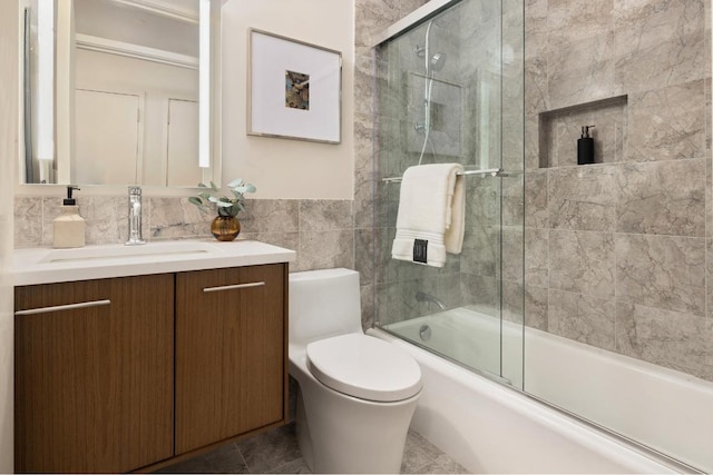 full bathroom featuring tile walls, vanity, bath / shower combo with glass door, and toilet