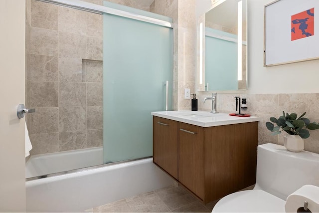 full bathroom featuring tile walls, enclosed tub / shower combo, vanity, toilet, and tile patterned floors