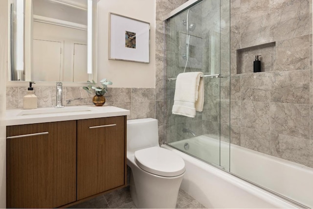 full bathroom with enclosed tub / shower combo, tile walls, vanity, and toilet