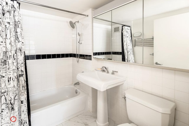 bathroom with toilet, shower / tub combo, and tile walls