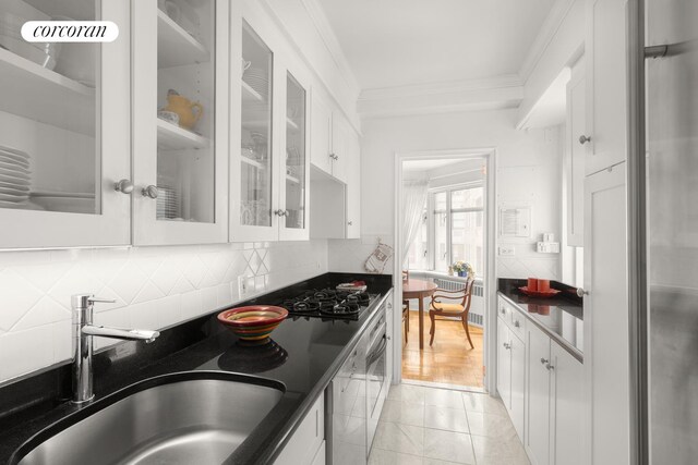 kitchen with backsplash, sink, crown molding, and white cabinetry