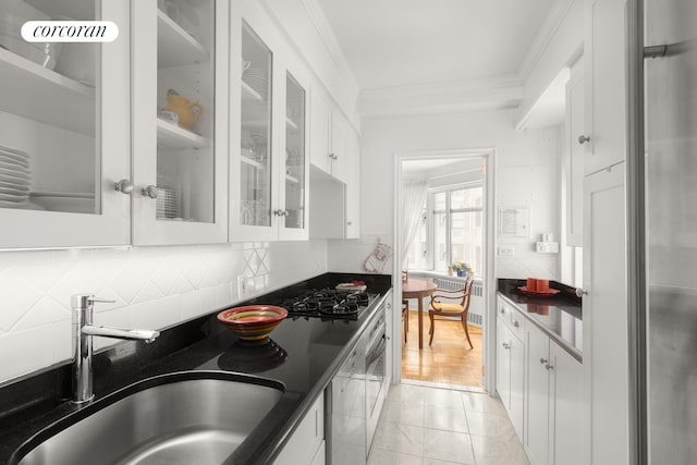 kitchen with crown molding, dark countertops, white cabinetry, and a sink