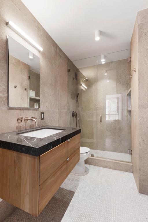 bathroom featuring tile walls, vanity, walk in shower, toilet, and tile patterned floors