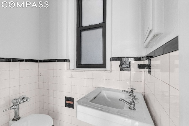 bathroom featuring sink, tile walls, and toilet