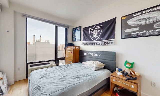 bedroom featuring wood finished floors, access to outside, and a wall unit AC