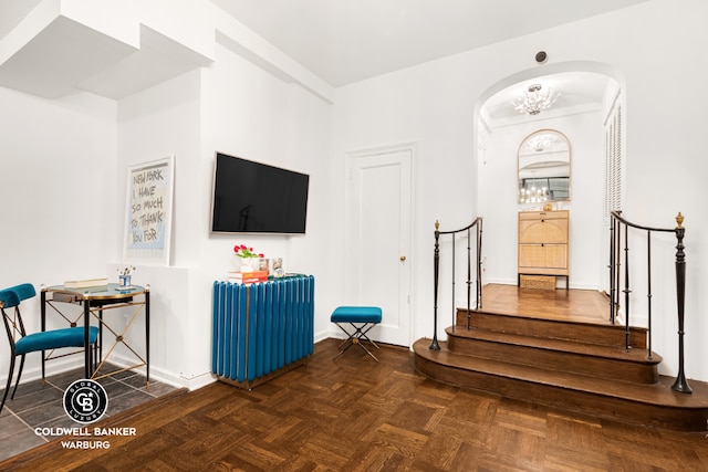 interior space with dark parquet floors and a notable chandelier