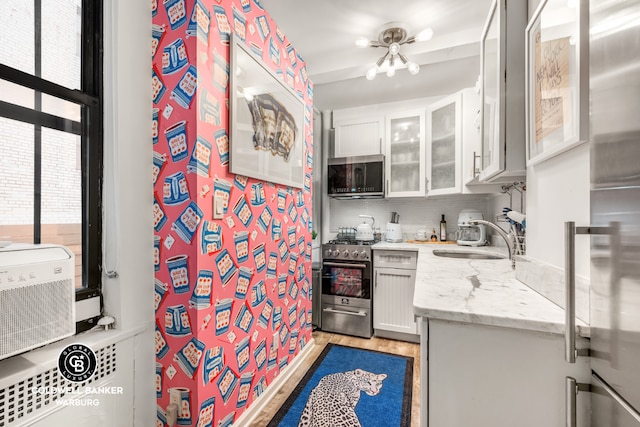 kitchen featuring white cabinets, appliances with stainless steel finishes, tasteful backsplash, sink, and light stone counters