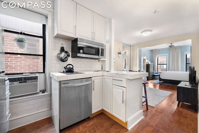 kitchen featuring white cabinetry, kitchen peninsula, appliances with stainless steel finishes, tile counters, and dark hardwood / wood-style flooring