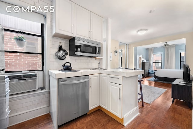 kitchen with stainless steel appliances, white cabinets, tile countertops, and dark wood-type flooring