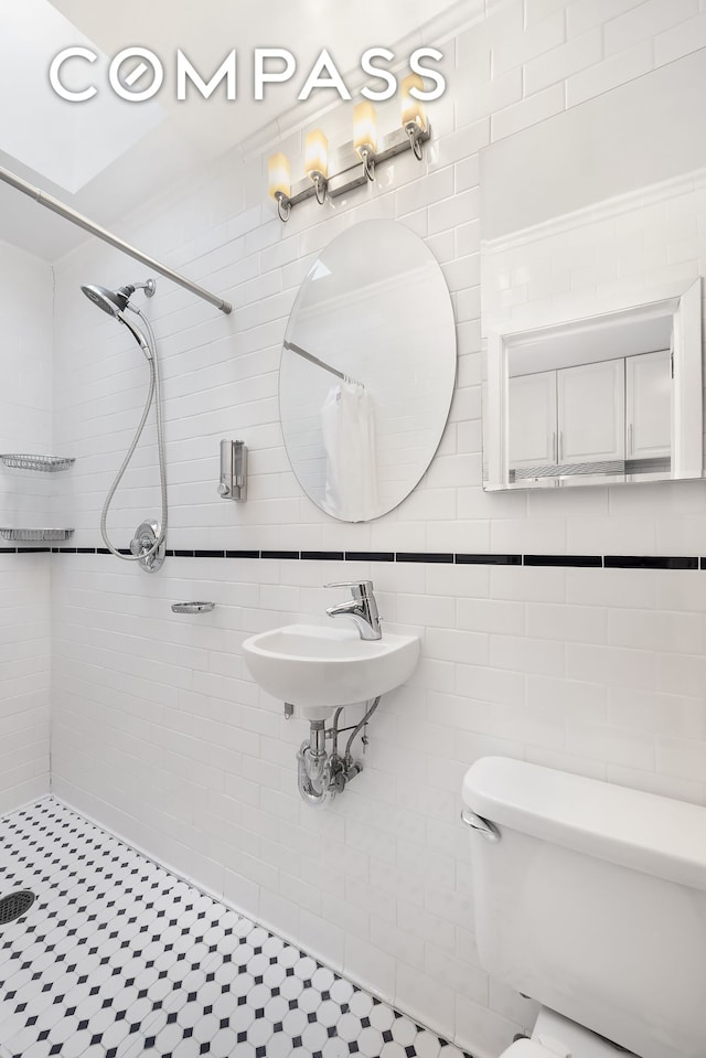 full bath with a sink, toilet, tile walls, and a tile shower