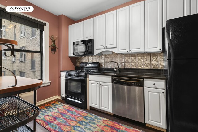 kitchen with dark countertops, white cabinetry, black appliances, and a sink