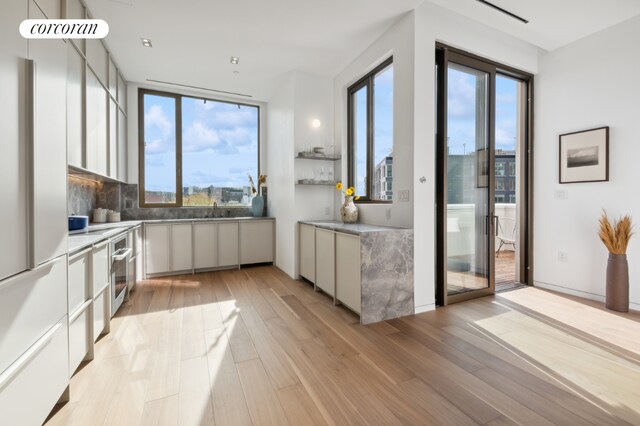 kitchen featuring sink, white cabinetry, tasteful backsplash, stainless steel oven, and light wood-type flooring