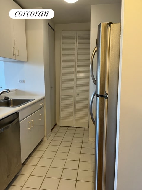 kitchen with a sink, white cabinetry, appliances with stainless steel finishes, light countertops, and light tile patterned floors