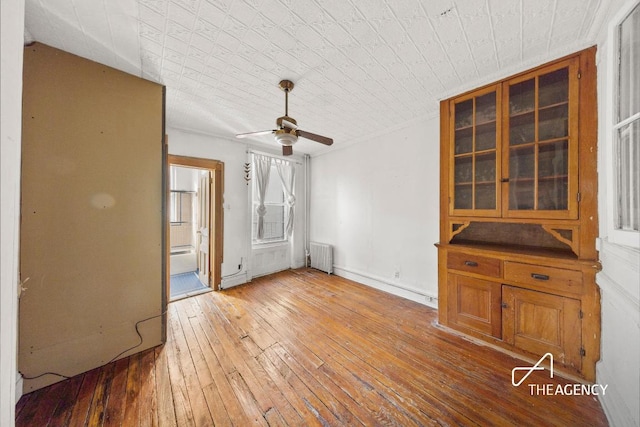 unfurnished living room featuring ceiling fan, radiator heating unit, and hardwood / wood-style floors