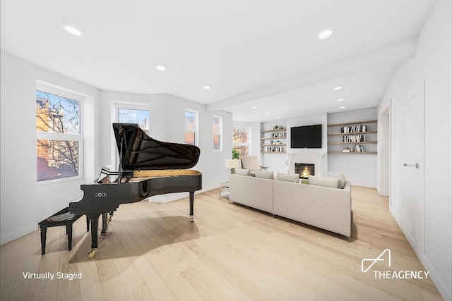 living room with beam ceiling, built in features, and light hardwood / wood-style flooring