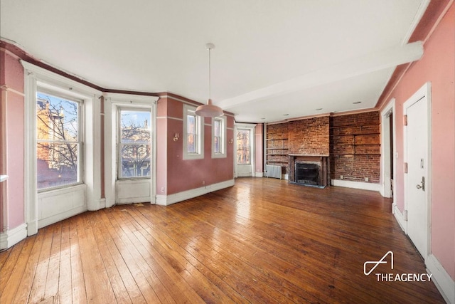 unfurnished living room with wood-type flooring, a brick fireplace, and crown molding