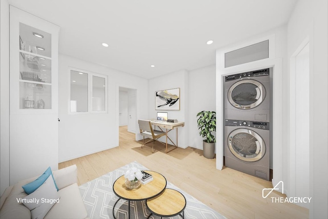 washroom with stacked washing maching and dryer and wood-type flooring