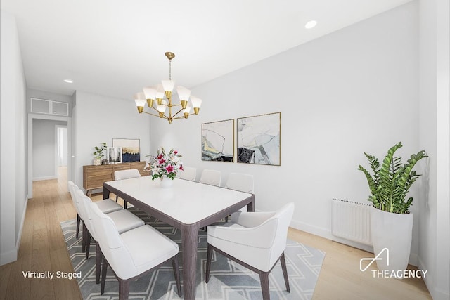 dining area featuring radiator heating unit, a notable chandelier, and light hardwood / wood-style flooring