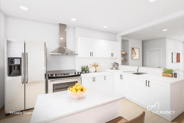 kitchen with wall chimney range hood, kitchen peninsula, sink, stainless steel appliances, and white cabinets