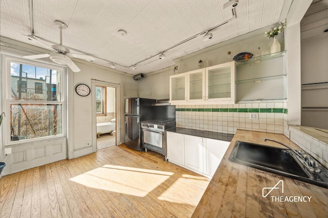 kitchen featuring stainless steel range oven, wood counters, white cabinetry, sink, and light wood-type flooring