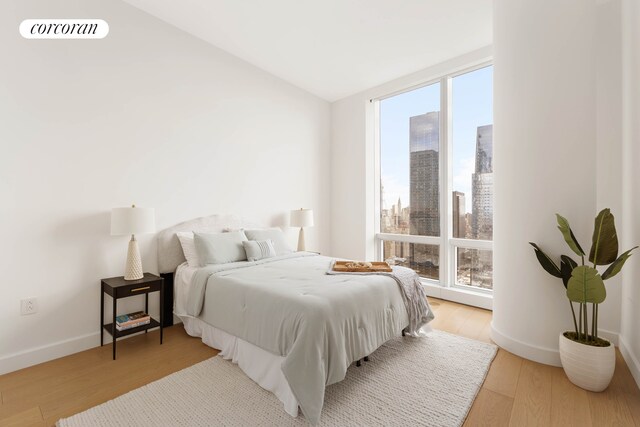 15 Hudson Yards Unit 67F, New York City, NY 10001 - bedroom featuring light wood finished floors, baseboards, lofted ceiling, and a view of city