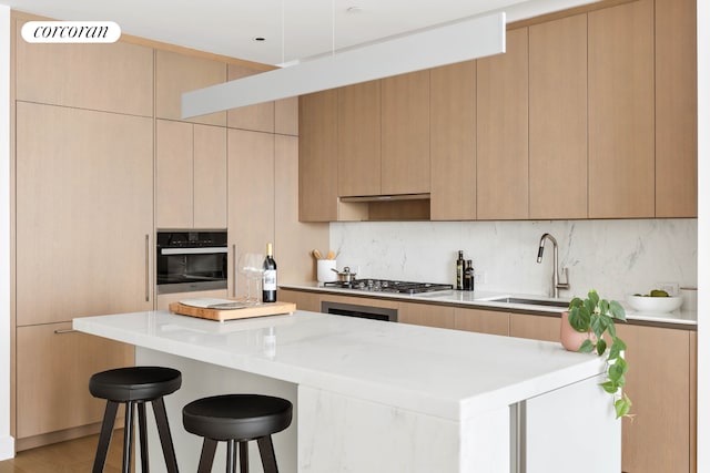 15 Hudson Yards Unit 67F, New York City, NY 10001 - kitchen featuring oven, a sink, stainless steel gas stovetop, a breakfast bar, and backsplash