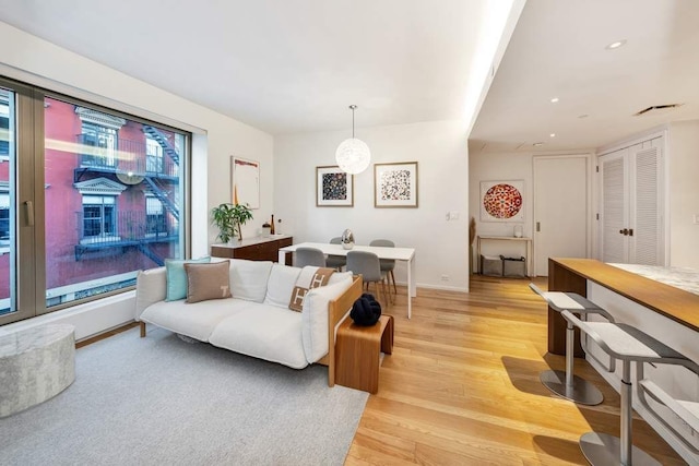 living room with light wood-style flooring, recessed lighting, visible vents, and baseboards