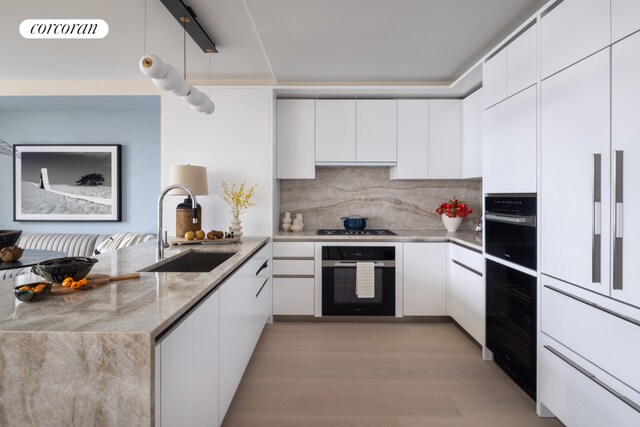 kitchen with sink, white cabinets, oven, gas stovetop, and light stone countertops