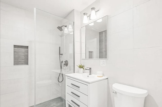 bathroom featuring tile walls, tiled shower, vanity, and toilet