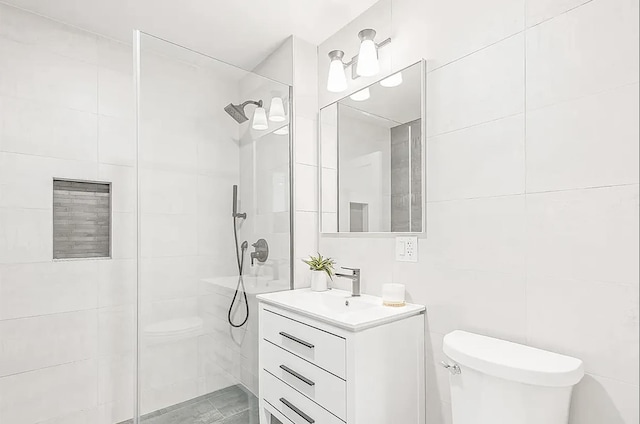 bathroom with tiled shower, toilet, vanity, and tile walls