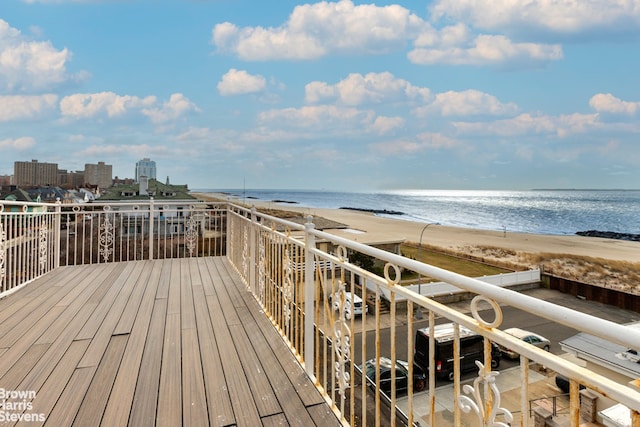 wooden deck with a water view and a view of the beach