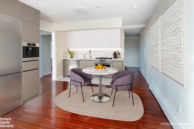 dining space with dark hardwood / wood-style floors, sink, crown molding, and a baseboard radiator